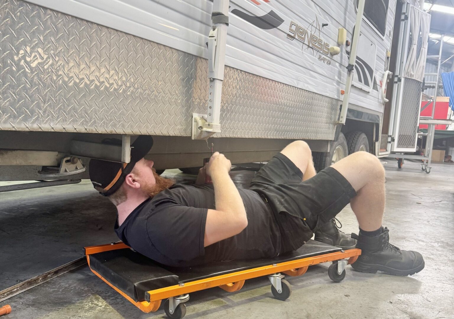 Vanaid technician working beneath a caravan